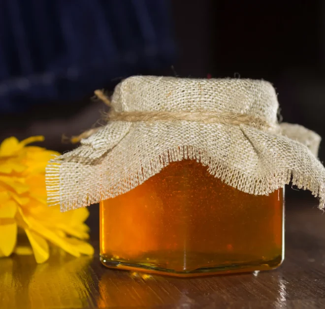 bee-honey-glass-jar-with-cover-burlap-yellow-flowers-dark-background